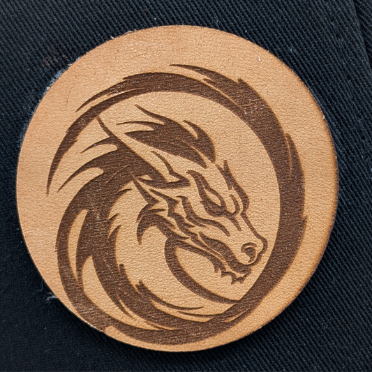 Up close view of laser engraved leather patch with the head of a dragon encased in a semi circle of fire. Fantasy Dragon Hat Mythical Accessories Emporium
