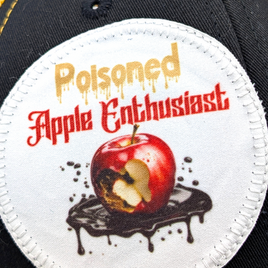 Up close view of the large round white polyester patch. On the top of the patch in gold is the word Poisoned with drips. Below this in red old english font is Apple Enthusiast. Under the text is a shiny read apple missing a bite surrounded in brown rot. Under the apple is a pool of dripping black poison.