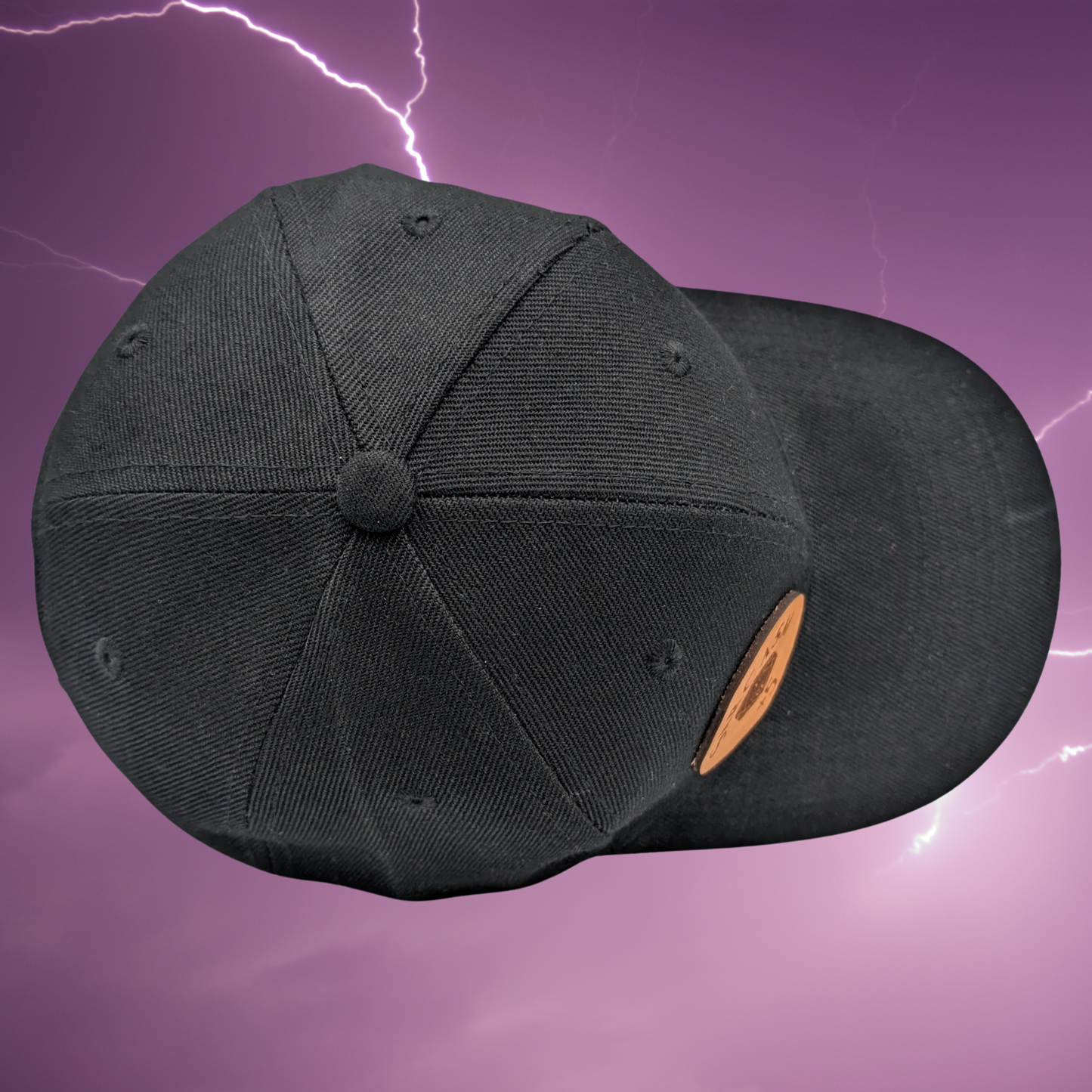 Top view of black cotton snapback hat. On the front right side of the hat is a round leather patch. The leather patch is laser engraved with Valkyrie Ride Or Die. From the word Or wings spread out to both sides. Valkyrie Warrior Viking Hat