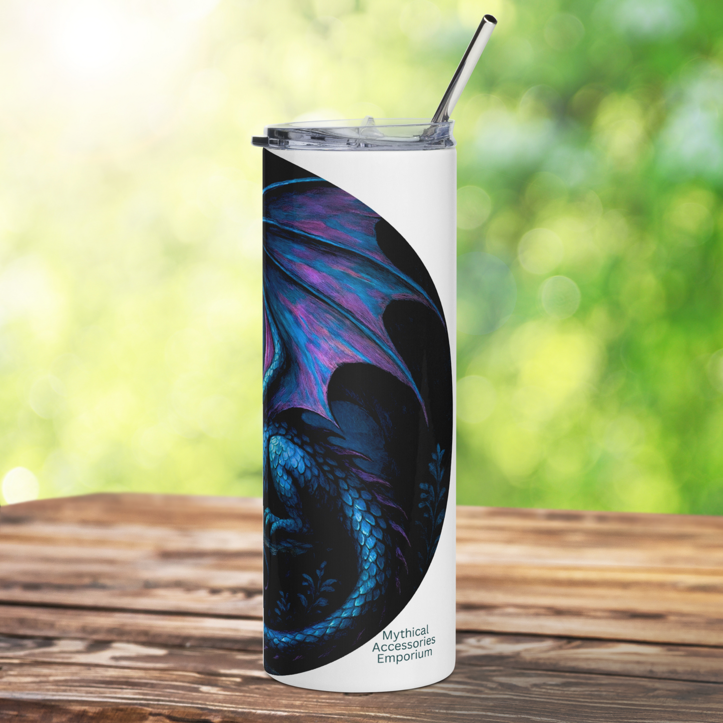 Insulated stainless steel fantasy dragon tumbler. This is a right side view of a blue dragon with purple highlights on the wings, horns, and tail. The dragon is resting on an outcrop of rocks at night. There is a dark cloudy sky with a full moon. Graphic is in blues and purple. You can see the stainless steel straw sticking up from the tumbler. The graphic is on a white tumbler.