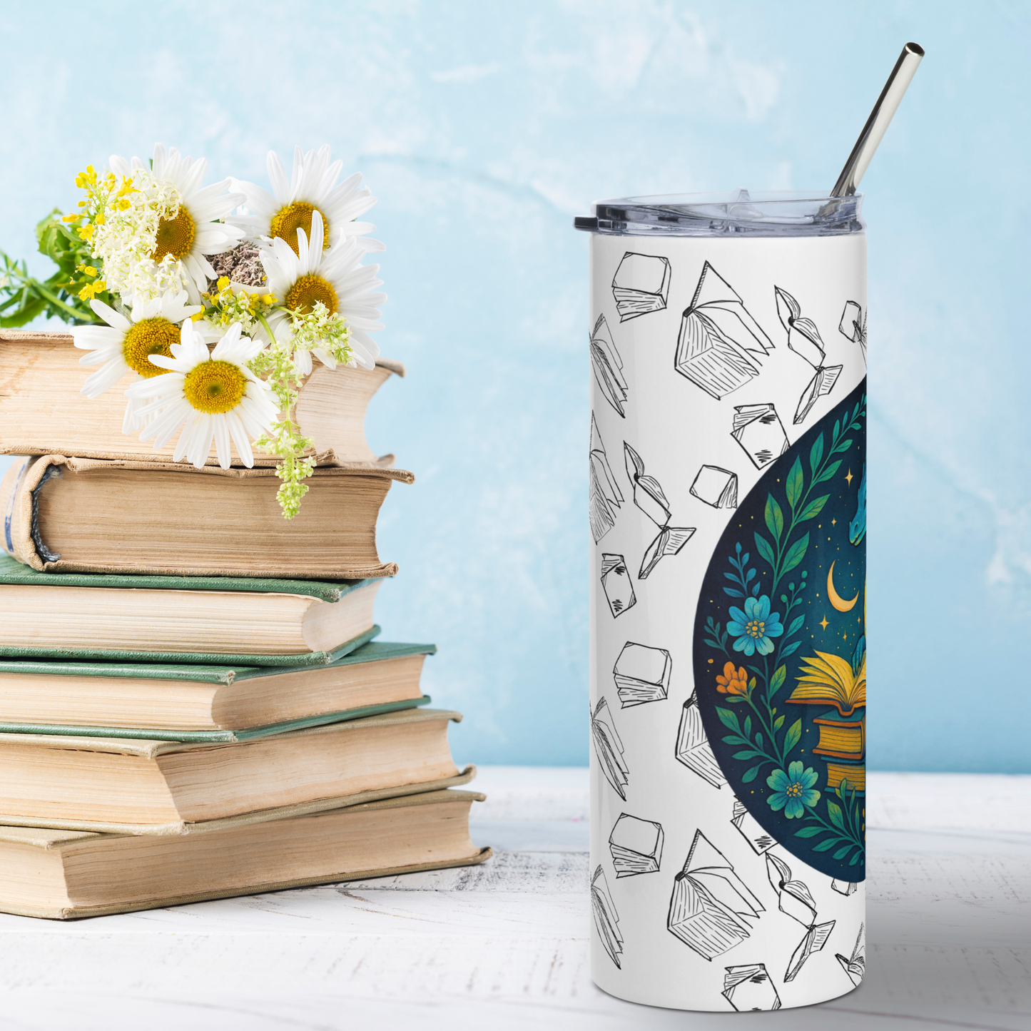 Left side view Book Dragon Graphic on White stainless steel 20 oz tumbler. Blue book dragon with horns perched on top of a stack of books. The top book is open for reading. Behind the dragon is the night sky with a crescent moon. Bordering the dragon are vines and flowers. Behind the circle graphic are black outlines of books surrounding the entire tumbler. You see the metal straw sticking out of the top. Booktok Gift for book lovers