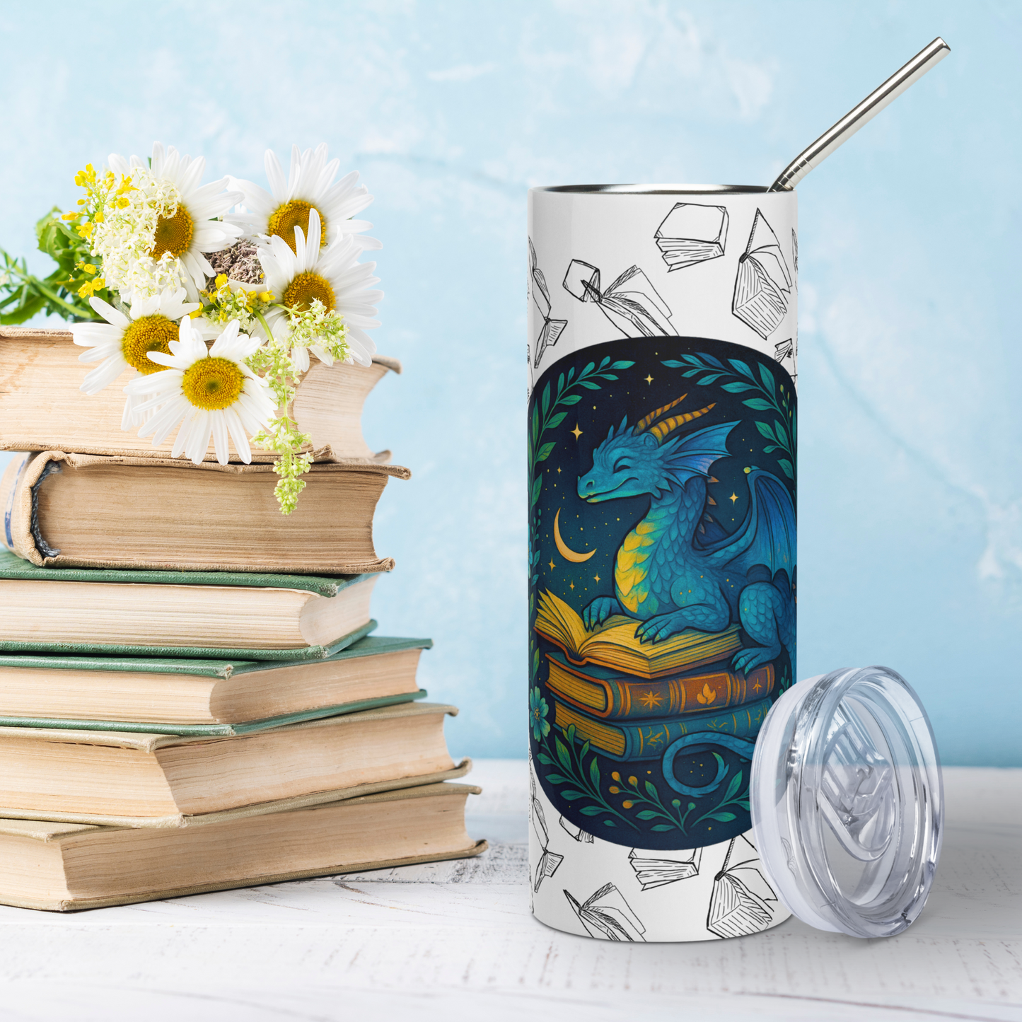 Front view Book Dragon Graphic on White stainless steel 20 oz tumbler with plastic lid leaning against bottle. Blue book dragon with horns perched on top of a stack of books. The top book is open for reading. Behind the dragon is the night sky with a crescent moon. Bordering the dragon are vines and flowers. Behind the circle graphic are black outlines of books surrounding the entire tumbler. You see the metal straw sticking out of the top. Bookish Gift for Fantasy Lovers
