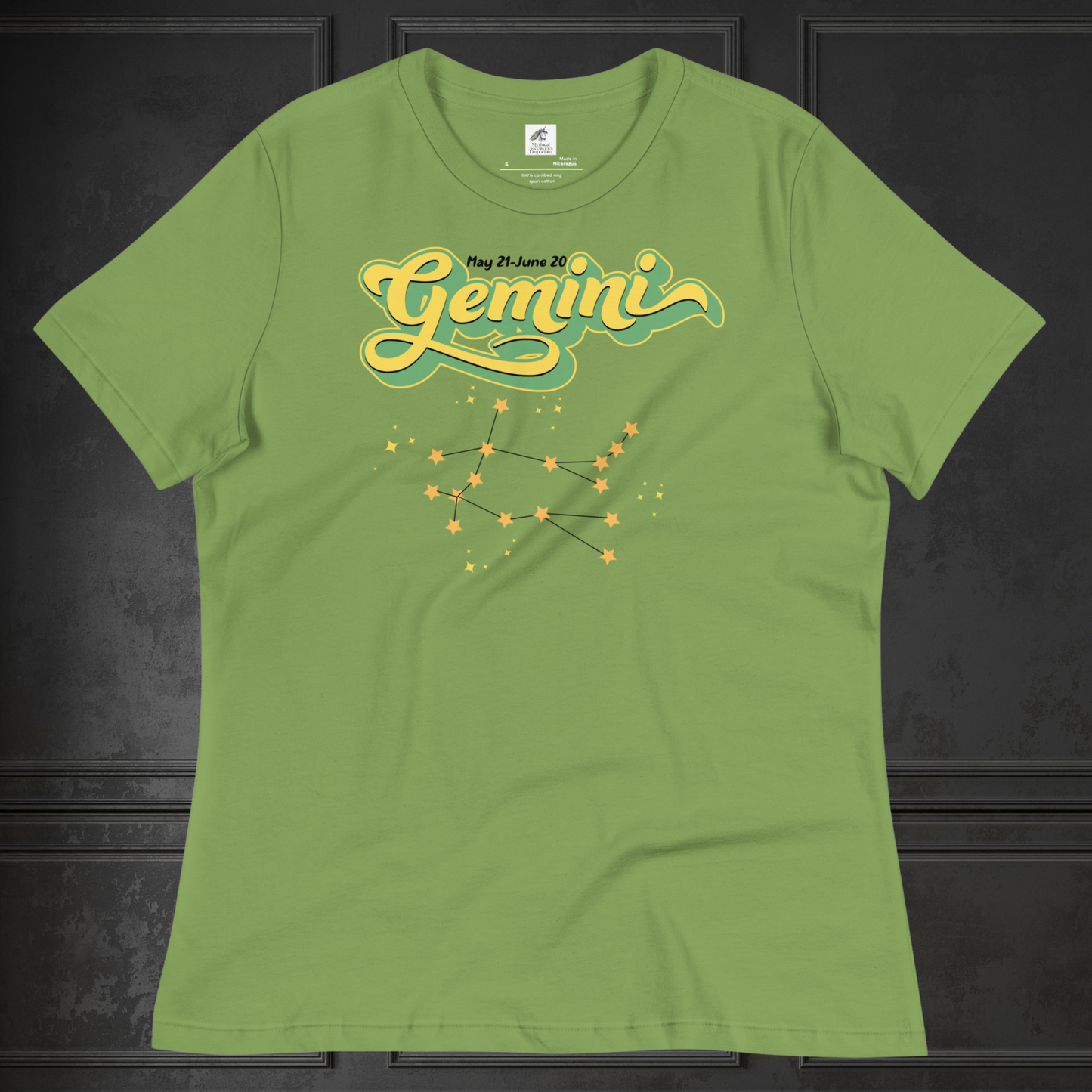 Front view of flat lay women's leaf green Gemini Tee. This Astrology T-Shirt has the word Gemini in large lemon yellow script shadowed in bright green for a 3-D effect. Above this it Says May 21-June 20. Under Gemini is the star constellation with yellow stars connected by a black line and yellow smaller stars surrounding this. The perfect May or June Birthday Gift for Her or yourself.