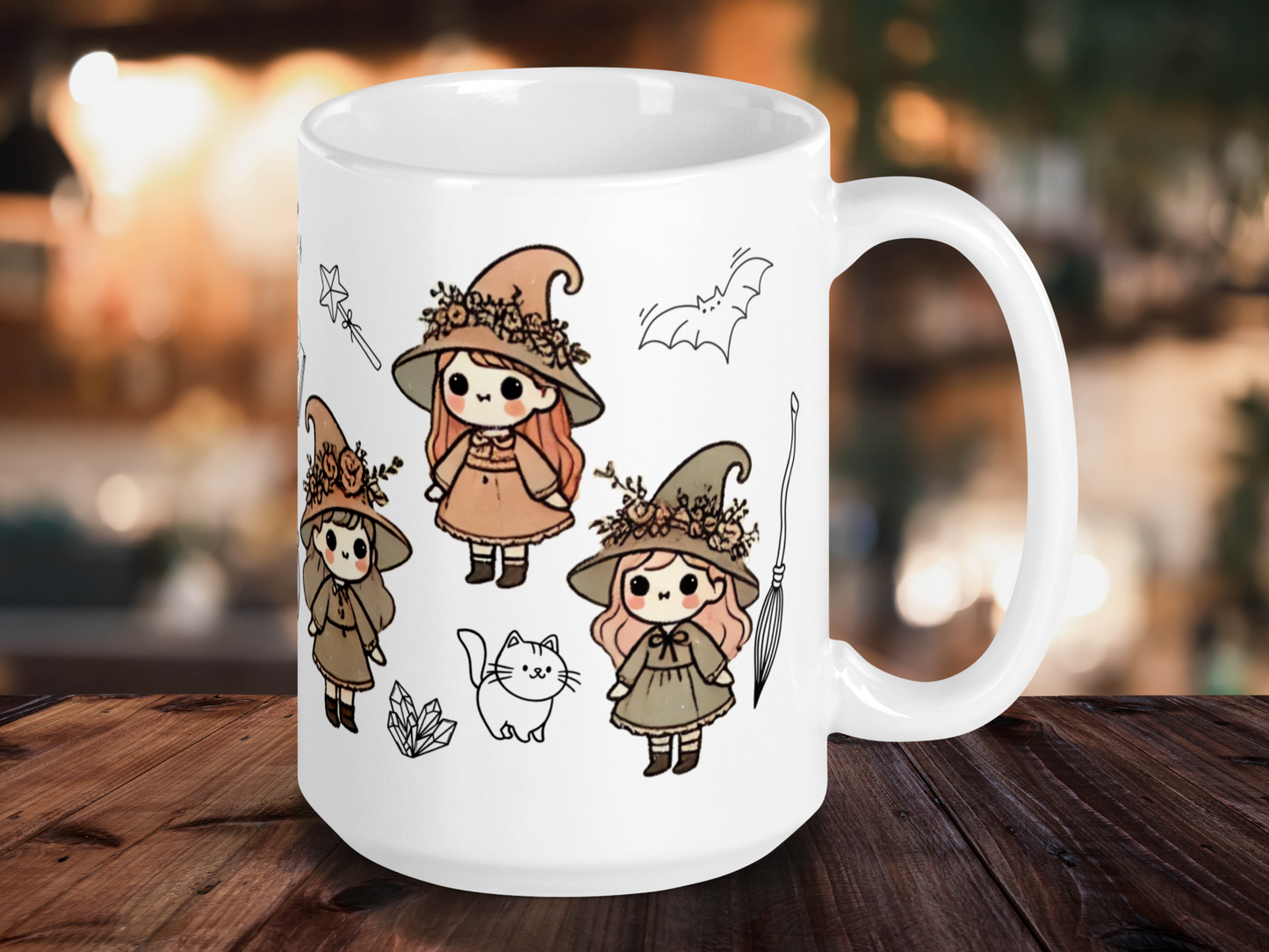 Vintage Kawaii Witch Mug, white ceramic mug with handle to the right. Three vintage chibi witches in earth tones are visible. Each hat is rimmed in flowers. Witches have brown and red hair. You can see the black outlines of a cat, crystals, a magic wand, and a bat. Perfect for Fall or Halloween.