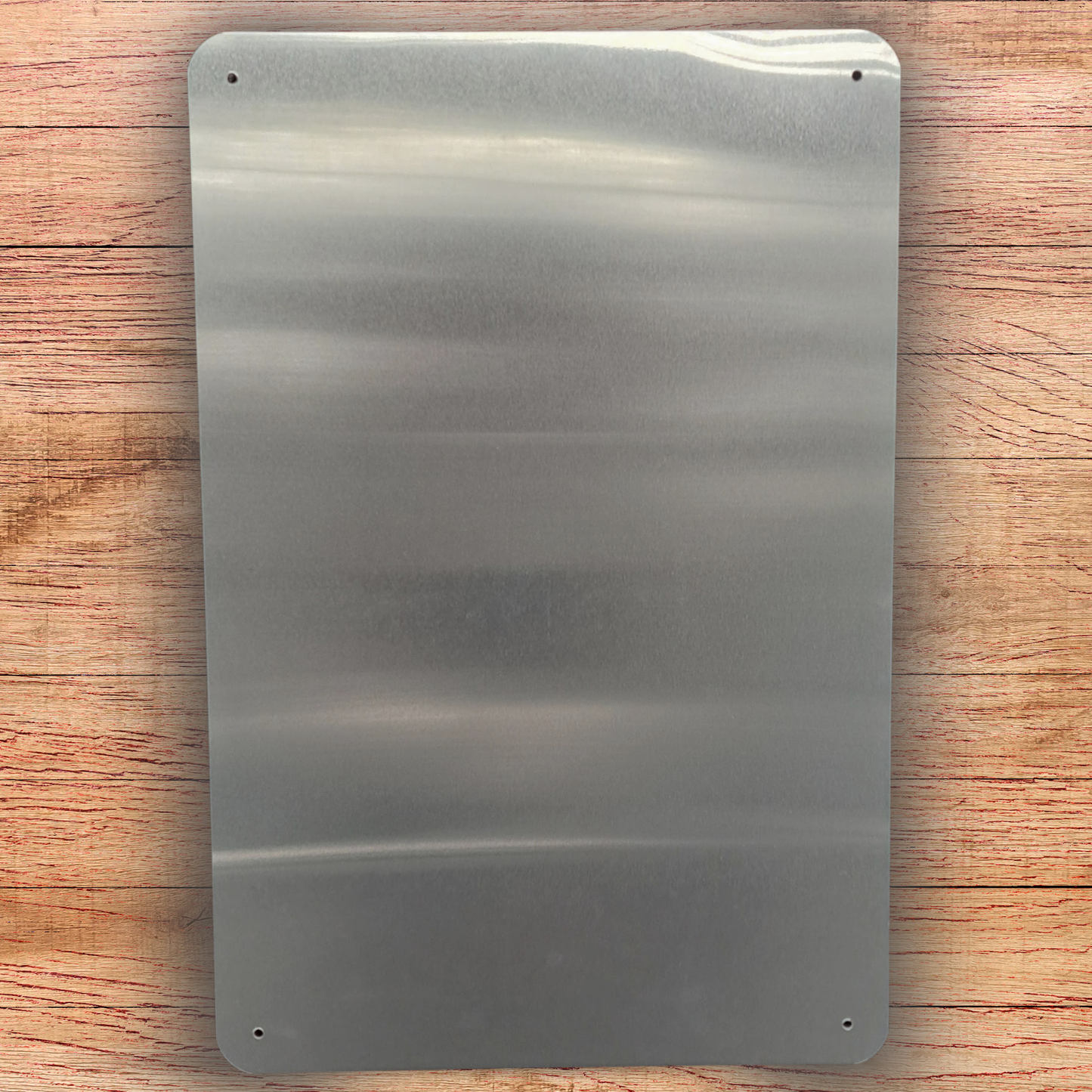 Back of Aluminum metal sign showing silver tone, rounded corners, and a hole in each corner for hanging.