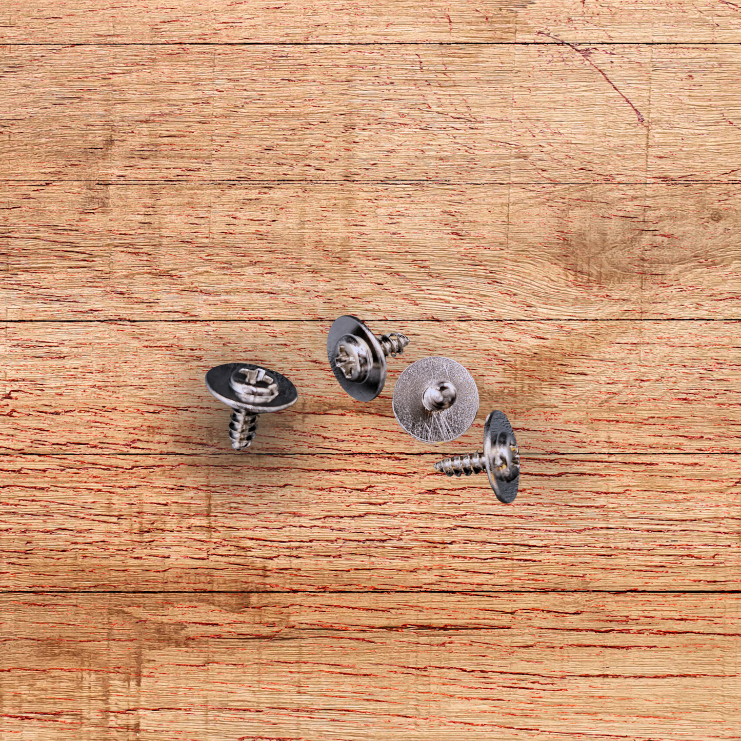 Four metal screws on a wooden surface. These are included with the metal sign for hanging.