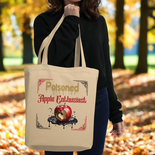 Front view held by model Natural Organic Tote Bag Poisoned Apple Enthusiast above a decaying apple sitting in a pool of poison