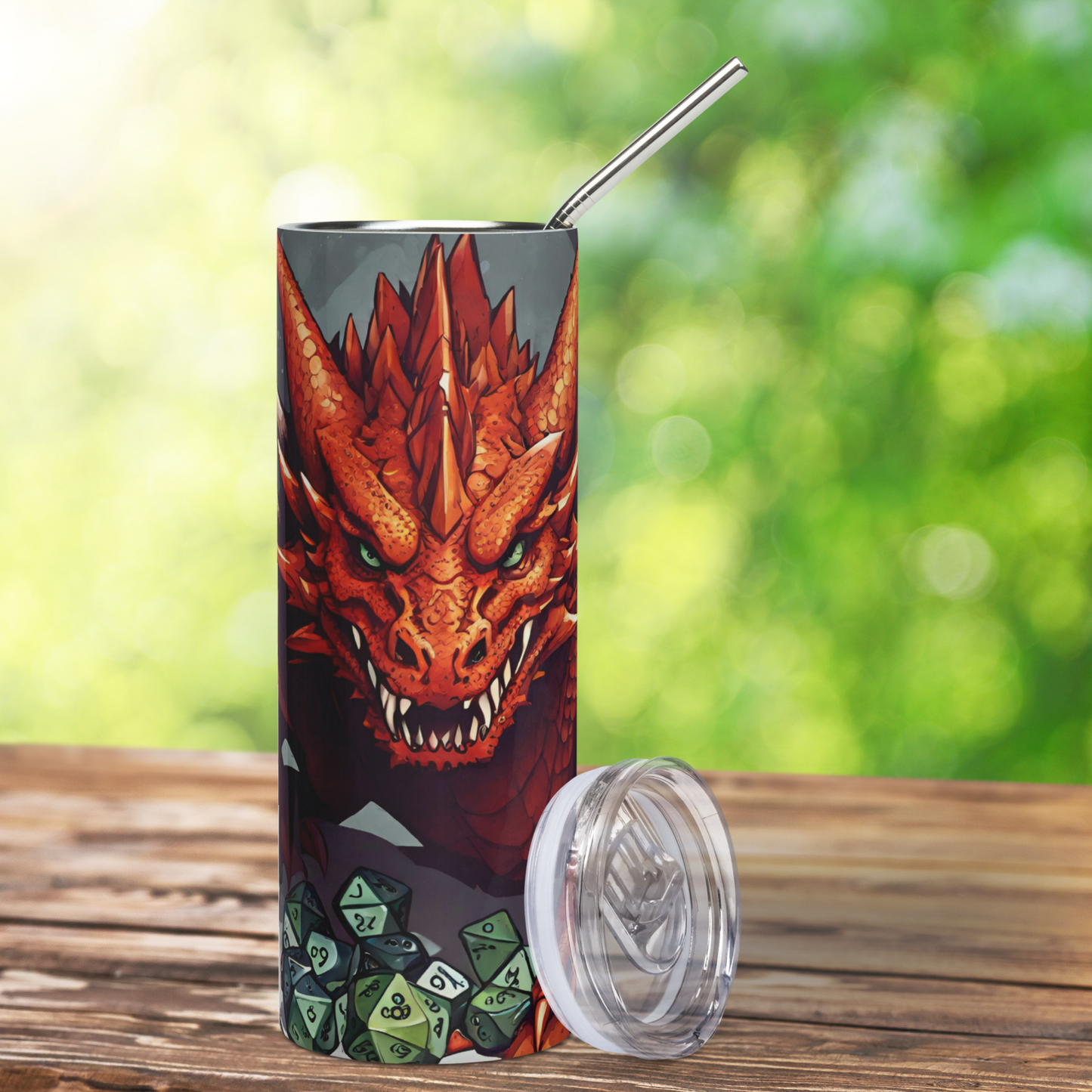 Red D20 Dragon Stainless Steel 20 oz Tumbler. View of the front, metal straw can be seen at the top of the tumbler, the BPA free plastic lid is leaning on the right side. Fierce red dragon with horns, green eyes, and sharp teeth. Leathery wings spread to each side it stalks forward over a treasure pile of TTRPG dice. DND coffee mug cup decor