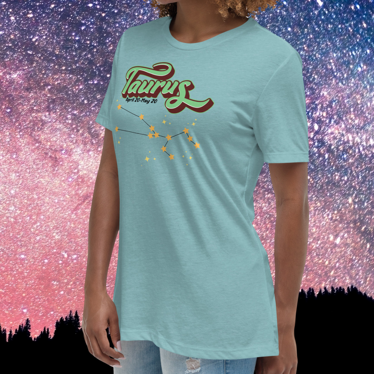 Left side view of model wearing heather blue lagoon women's Taurus Tee. Crew neck neckline and short sleeves going to mid upper arm, hem falls below hip. This Astrology T-Shirt has the word Taurus in large leaf green script shadowed in deep brown for a 3-D effect. Below this it Says April 20-May 20. At the bottom is the star constellation for Taurus with yellow stars connected by a black line and smaller stars surrounding the constellation. The perfect April or May Birthday Gift for Her or yourself.