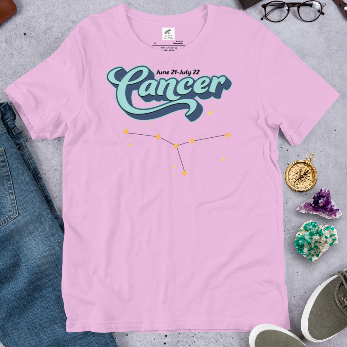 Front view of flat lilac men's Cancer Tee. This astrology Cancer T-Shirt has the word Cancer in large light blue script shadowed in deep blue for a 3-D effect. Above this it Says June 21-July 22. Under Cancer is the zodiac star constellation with yellow stars connected by a black line and lighter yellow smaller stars surrounding this. The perfect June or July Birthday Gift for him or yourself.