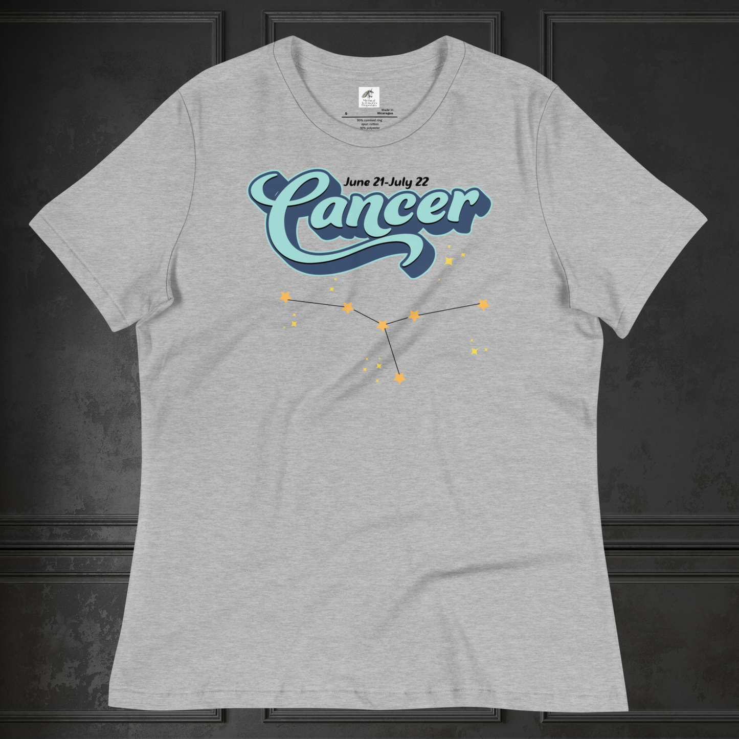 Front view of flat lay athletic heather grey women's Cancer Tee. This astrology Cancer T-Shirt has the word Cancer in large light blue script shadowed in deep blue for a 3-D effect. Above this it Says June 21-July 22. Under Cancer is the zodiac star constellation with yellow stars connected by a black line and lighter yellow smaller stars surrounding this. The perfect June or July Birthday Gift for Her or yourself.