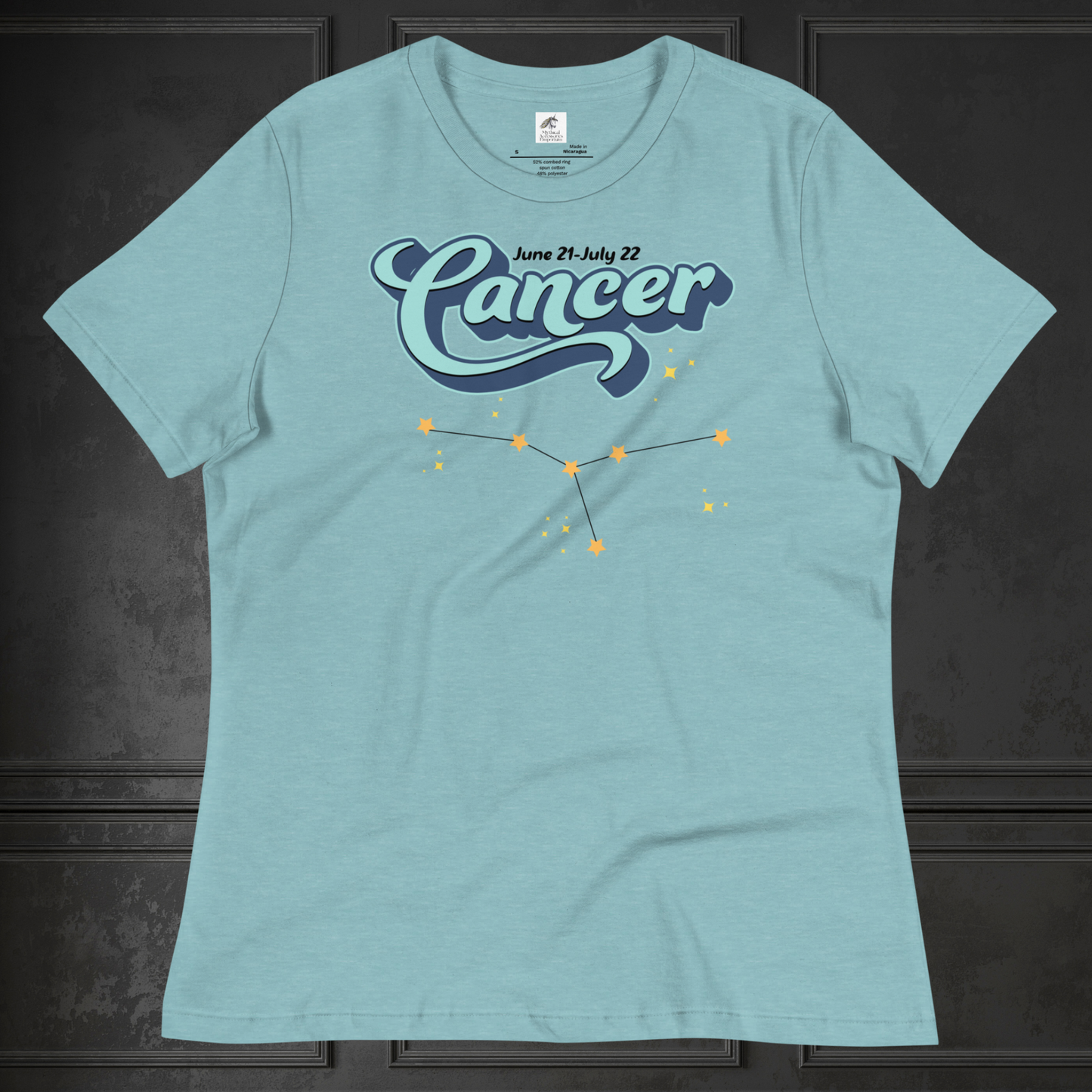 Front view of flat lay of heather blue lagoon women's Cancer Tee. This astrology Cancer T-Shirt has the word Cancer in large light blue script shadowed in deep blue for a 3-D effect. Above this it Says June 21-July 22. Under Cancer is the zodiac star constellation with yellow stars connected by a black line and lighter yellow smaller stars surrounding this. The perfect June or July Birthday Gift for Her or yourself.