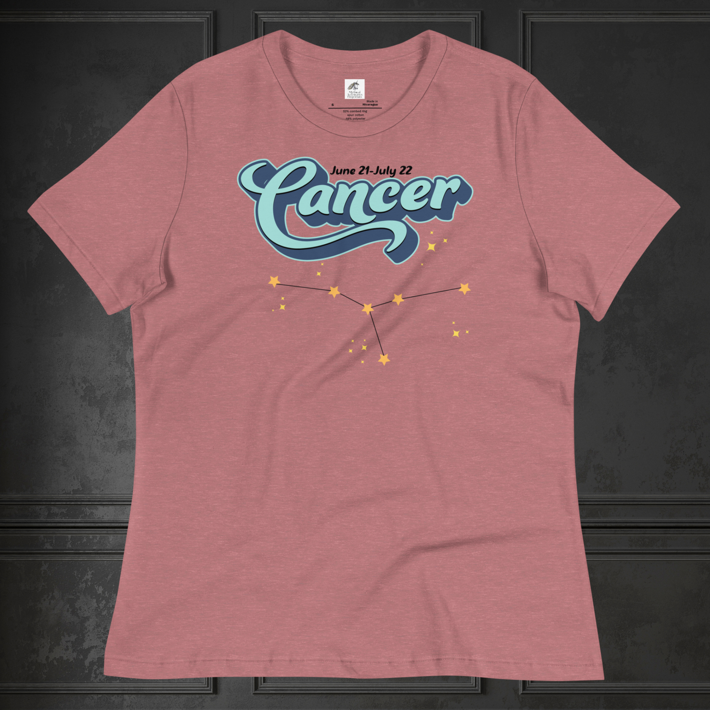 Front view of flat lay heather mauve (light red) women's Cancer Tee. This astrology Cancer T-Shirt has the word Cancer in large light blue script shadowed in deep blue for a 3-D effect. Above this it Says June 21-July 22. Under Cancer is the zodiac star constellation with yellow stars connected by a black line and lighter yellow smaller stars surrounding this. The perfect June or July Birthday Gift for Her or yourself.