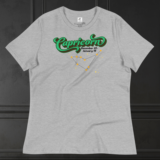 Front view of flat athletic heather (grey) women's Capricorn Tee. This astrology T-Shirt has the word Capricorn in a large green script shadowed in black for a 3-D effect. Below this it Says December 22-January 19. Under Capricorn is the zodiac star constellation with yellow stars connected by a black line and lighter yellow smaller stars surrounding this. The perfect December or January Birthday Gift for Her or yourself.