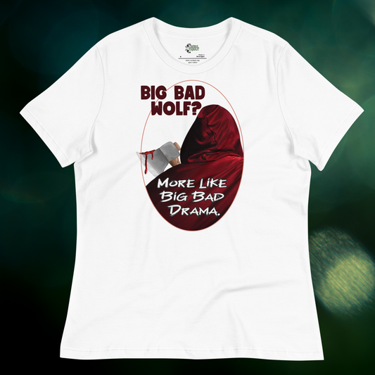 Red Riding Hood Women's Dark Fantasy T-Shirt. Front View White Graphic Tee flat view on dark background. Oval frame with thin red border. You can see the back of red riding hood with hood up. Bloody axe over her shoulder. Text Big Bad Wolf? More Like Big Bad Drama. Crew neck with short sleeves, relaxed fit. Big Bad Wolf booktok gift for her