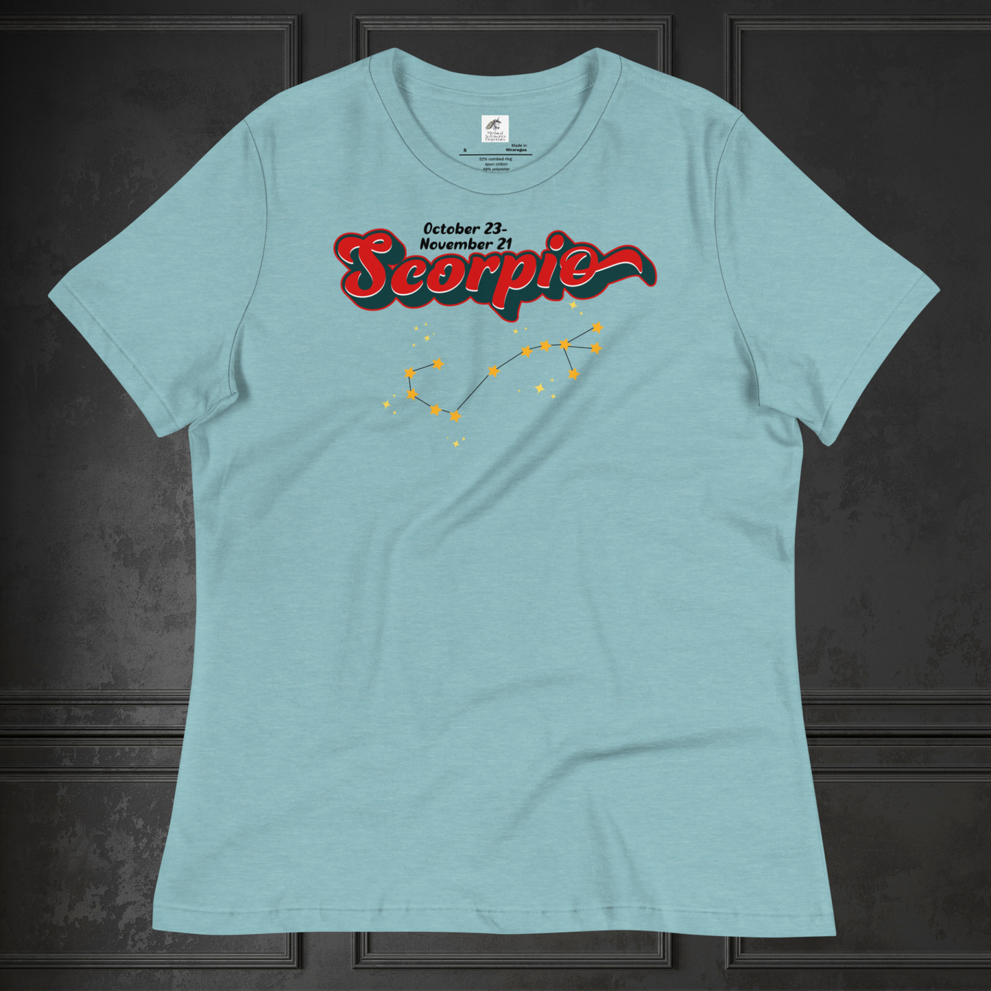 Front view of flat Heather blue lagoon women's Scorpio Tee. This astrology Scorpio T-Shirt has the word Scorpio in large red script shadowed in deep dark blue for a 3-D effect. Above this it Says October 23-November 21st. Under Scorpio is the zodiac star constellation with yellow stars connected by a black line and lighter yellow smaller stars surrounding this. The perfect October or November Birthday Gift for her or yourself.