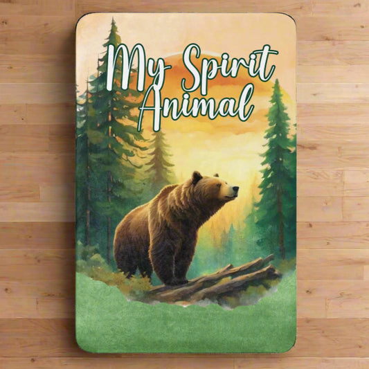 My Spirit Animal bear sherpa blanket. Front view. Grizzly Bear paused in front of logs walking through the forest framed in a sunset. My Spirit Animal text at the top in white script.
