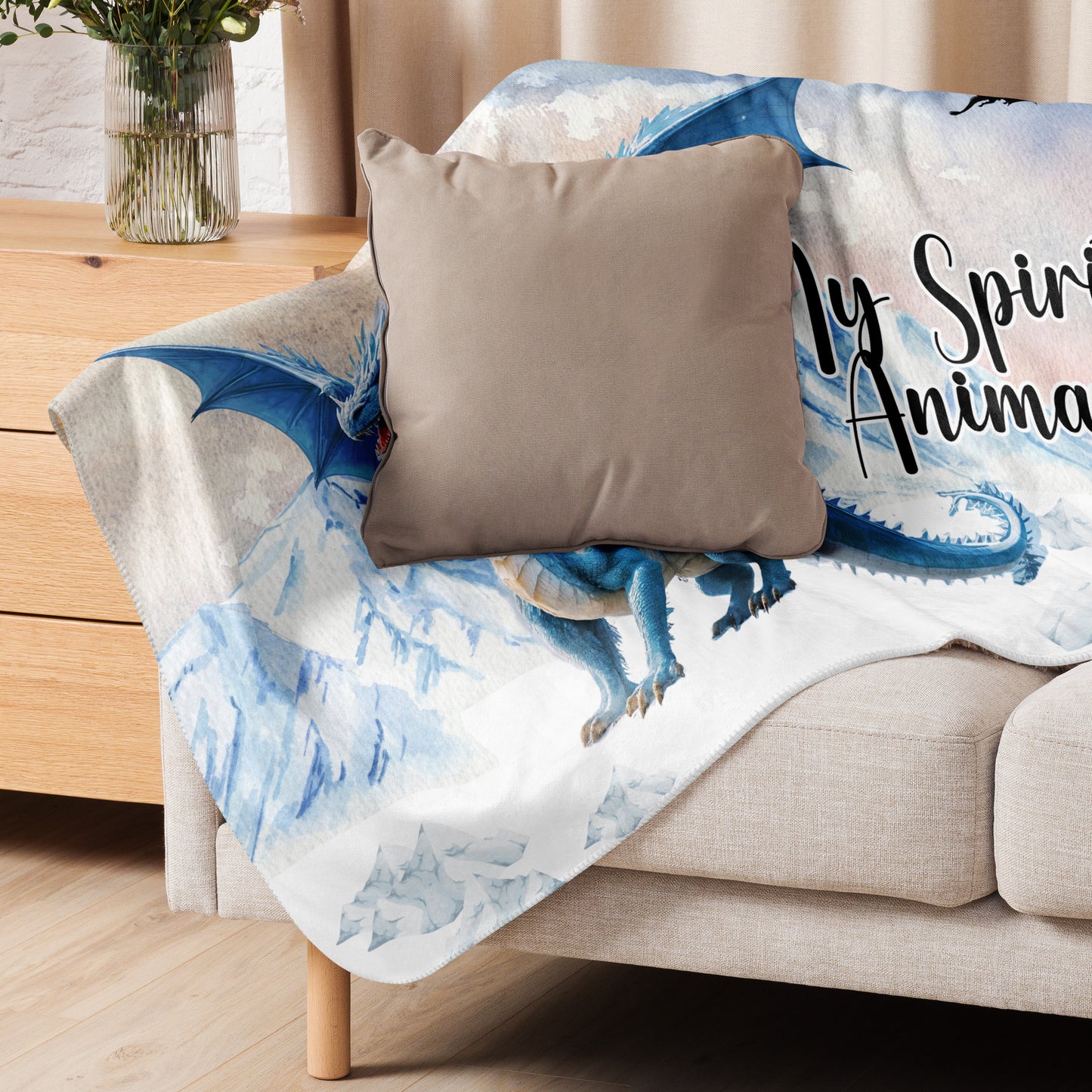 My Spirit Animal Dragon Blanket. Blanket is over the side and back of a loveseat. Blue Ice Dragon with wings spread standing in front of snow capped mountain range with a dragon silhouette flying above. Ice Dragon Fantasy Bookish Gift, Dungeons and Dragons DND Dungeon Master Gift, Fantasy Home Decor
