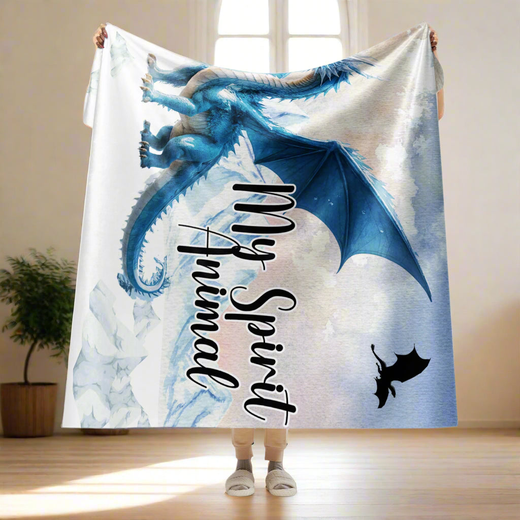 My Spirit Animal Dragon Blanket. Model holding blanket over her head size 60x80. Blanket is partially folded over at the top over her hands. Bottom of blanket reaches mid way between her knees and ankles. This is a twin size blanket or a queen bed throw blanket. Blue Ice Dragon with wings spread standing in front of snow capped mountain range with a dragon silhouette flying above within. Ice Dragon Fantasy Bookish Gift, Dungeons and Dragons DND Dungeon Master Gift, Fantasy Home Decor