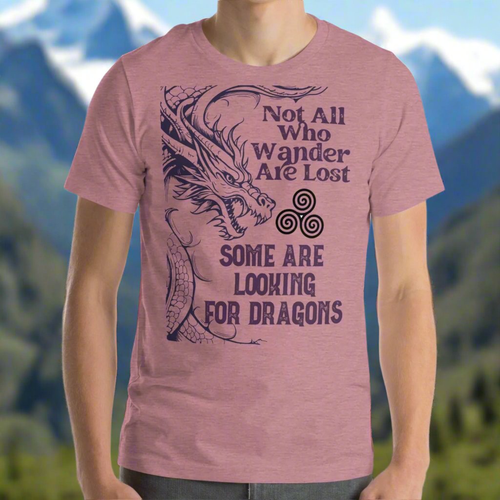 Heather orchid men’s T-shirt, front view. Right side features a dragon in smoky gray-purple with the Celtic triskele symbol emerging from its nostrils. Text above reads "Not All Who Wander Are Lost," with "Some Are Looking for Dragons" below.