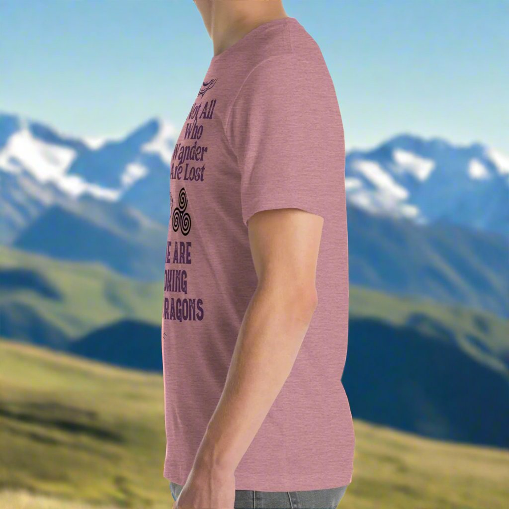 Heather orchid men’s T-shirt, left side view. Right side features a dragon in smoky gray-purple with the Celtic triskele symbol emerging from its nostrils. Text above reads "Not All Who Wander Are Lost," with "Some Are Looking for Dragons" below.