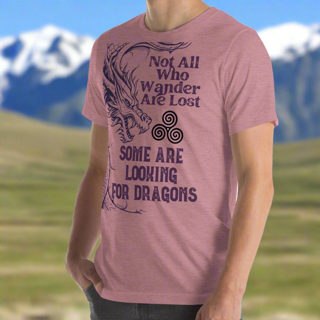 Heather orchid men’s T-shirt, front left view. Right side features a dragon in smoky gray-purple with the Celtic triskele symbol emerging from its nostrils. Text above reads "Not All Who Wander Are Lost," with "Some Are Looking for Dragons" below.