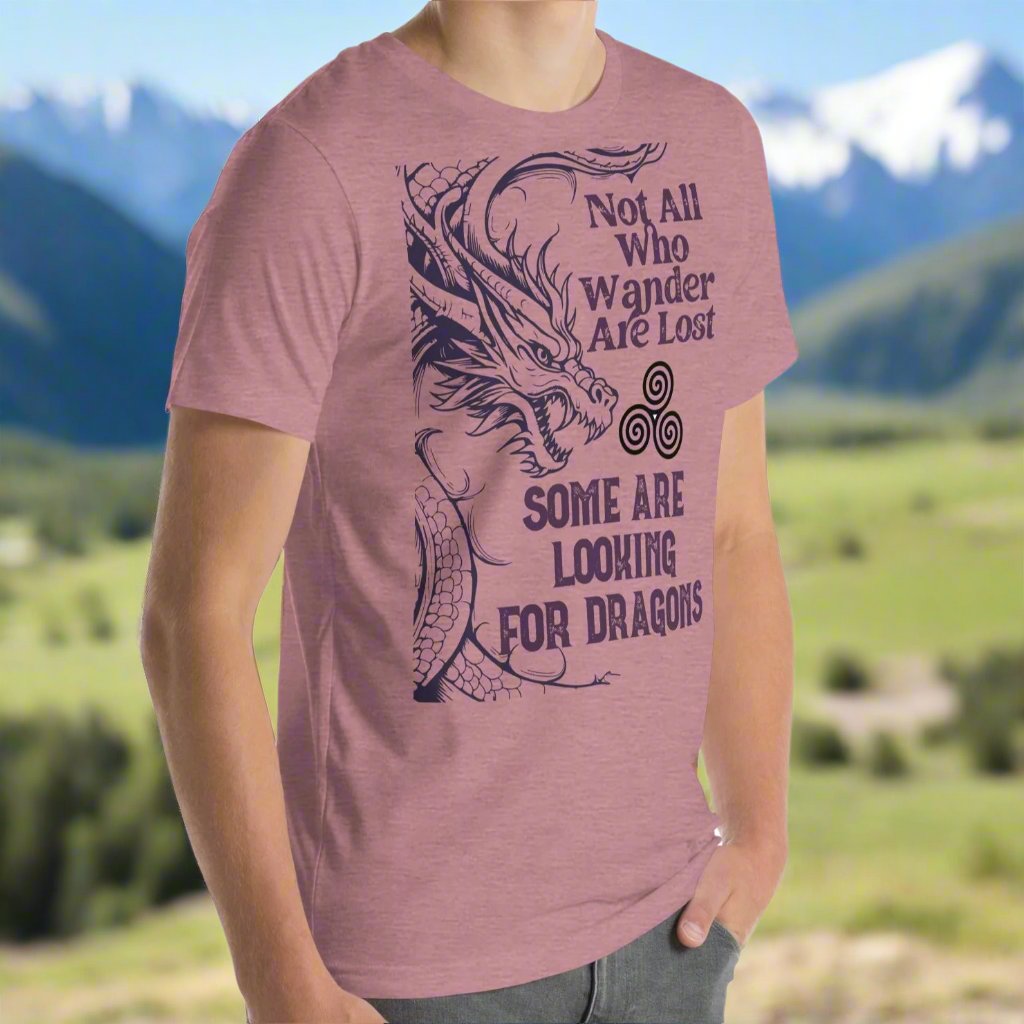 Heather orchid men’s T-shirt, front right view. Right side features a dragon in smoky gray-purple with the Celtic triskele symbol emerging from its nostrils. Text above reads "Not All Who Wander Are Lost," with "Some Are Looking for Dragons" below.
