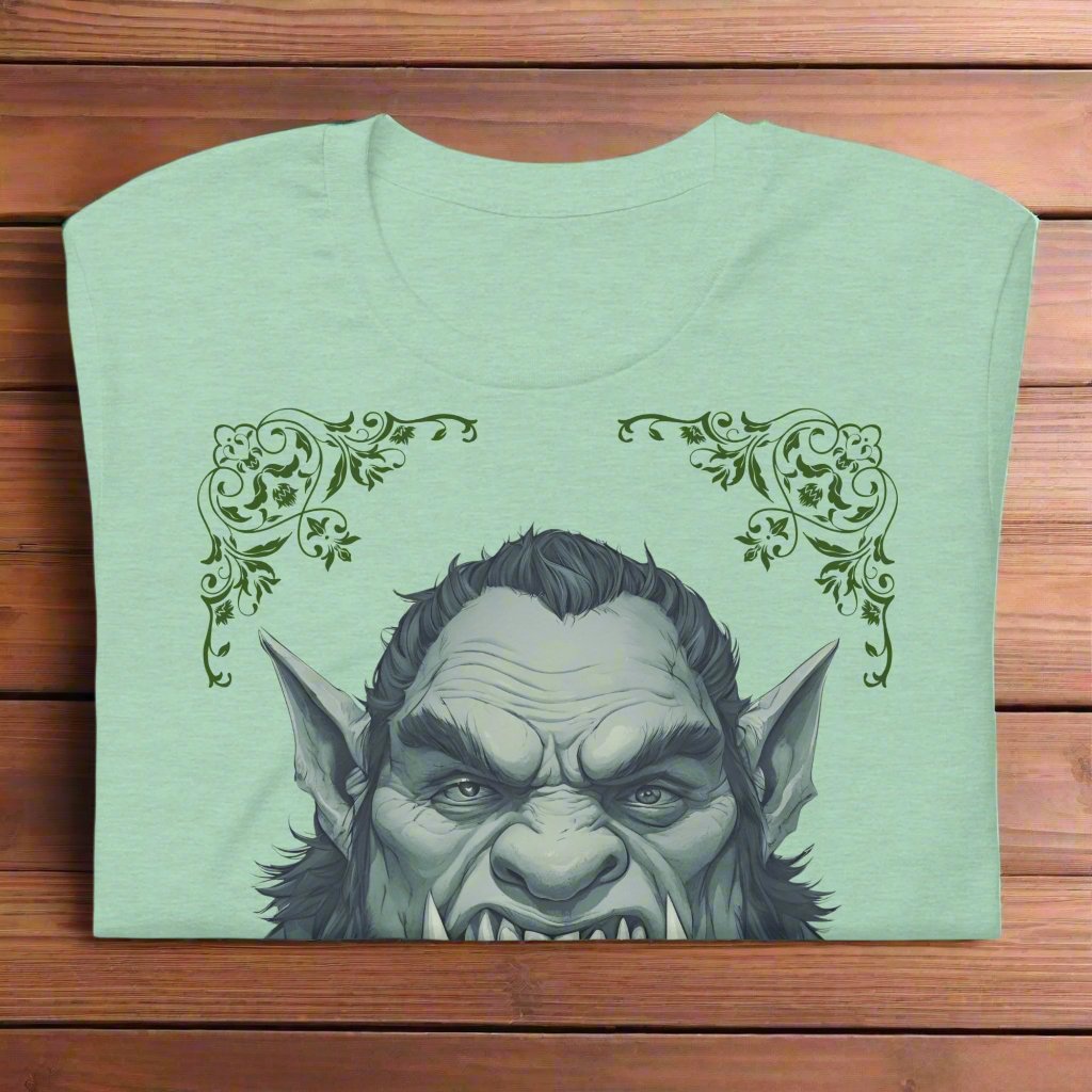 Front view of flat folded Men's heather prism mint Graphic Tee with a black and white orc on the front. The orcs lower canines jut up as tusks over his top lip. He has a bulbous nose, eyebrows drawn down into a fierce expression, a large forehead, large pointed ears, his hair is black and pulled back with a widows peak, he has hair down the sides of his face and a medium sized beard. Framing the orc in four corners is 1920s retro floral border in dark green. This is a regular fit men's tshirt