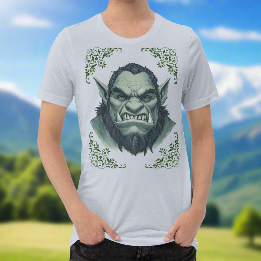Front view of Men's Tan Light blue Tee with a black and white orc on the front. The orcs lower canines jut up as tusks over his top lip. He has a bulbous nose, eyebrows drawn down into a fierce expression, a large forehead, large pointed ears, his hair is black and pulled back with a widows peak, he has hair down the sides of his face and a medium sized beard. Framing the orc in four corners is 1920s retro floral border in dark green. This is a regular fit men's tshirt or a unisex shirt.