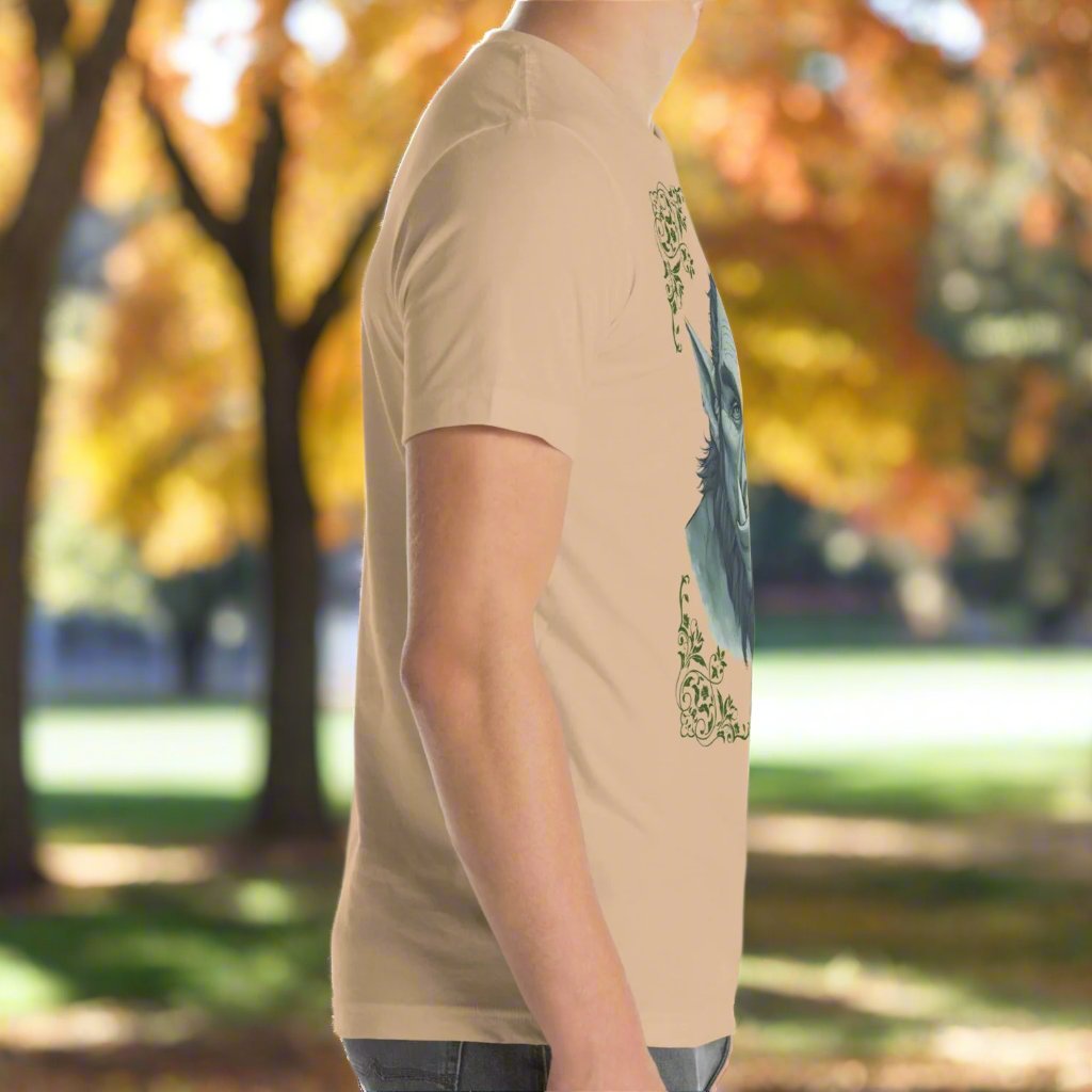 right side view of Men's Tan Graphic Tee with a black and white orc on the front. The orcs lower canines jut up as tusks over his top lip. He has a bulbous nose, eyebrows drawn down into a fierce expression, a large forehead, large pointed ears, his hair is black and pulled back with a widows peak, he has hair down the sides of his face and a medium sized beard. Framing the orc in four corners is 1920s retro floral border in dark green. This is a regular fit men's tshirt or a unisex shirt.