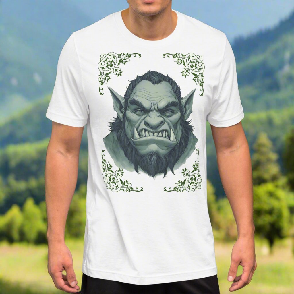 Front view of Men's White Graphic Tee with a black and white orc on the front. The orcs lower canines jut up as tusks over his top lip. He has a bulbous nose, eyebrows drawn down into a fierce expression, a large forehead, large pointed ears, his hair is black and pulled back with a widows peak, he has hair down the sides of his face and a medium sized beard. Framing the orc in four corners is 1920s retro floral border in dark green. This is a regular fit men's tshirt or a unisex shirt.