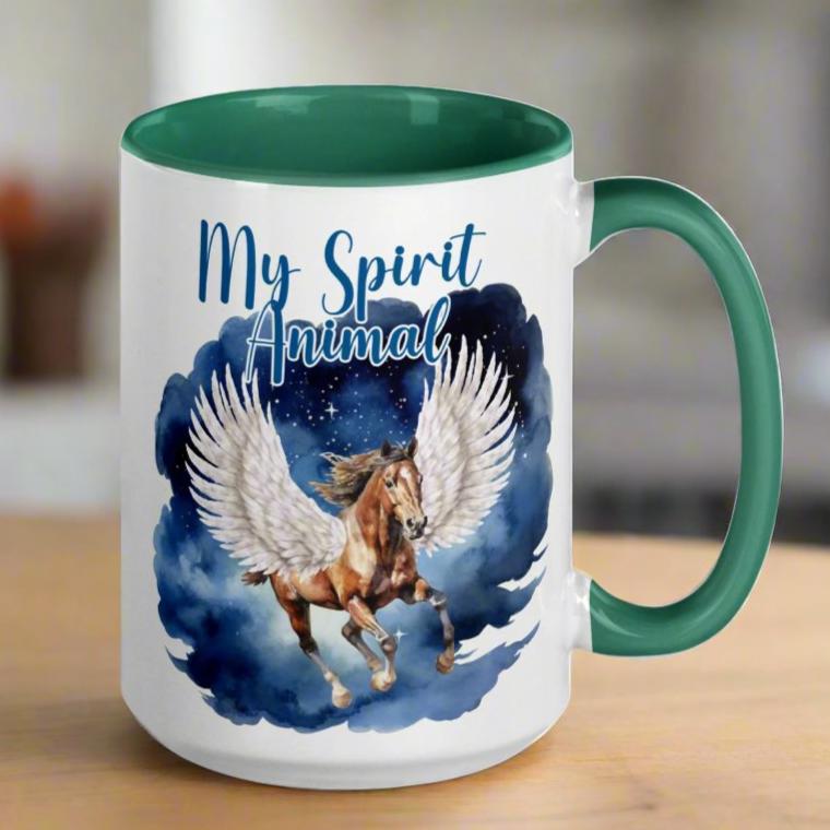 My Spirit Animal Pegasus Coffee Mug, white ceramic mug with handle on right, green interior and handle, Pegasus white feathered wings on a Pinto with a dark brown mane and tail, galloping against a background of clouds and stars. Mythical Accessories