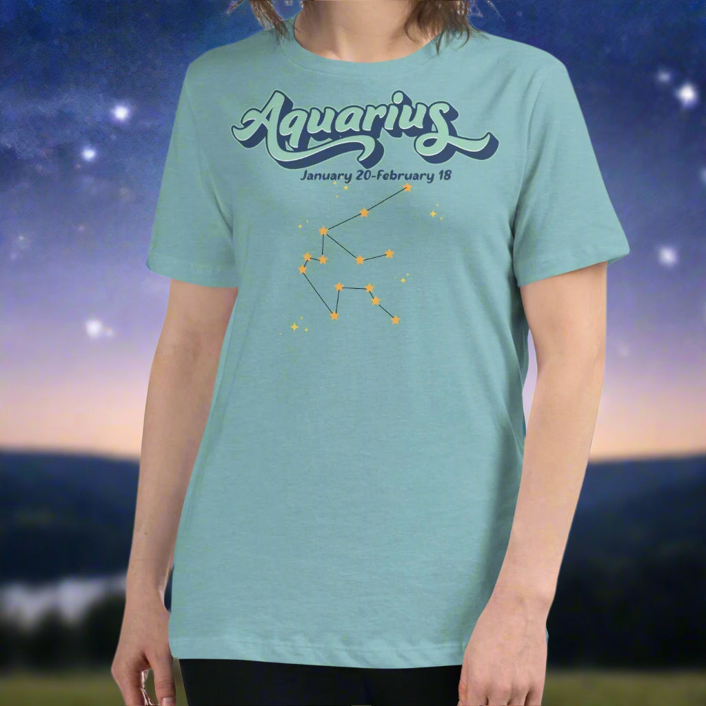 Woman in a heather blue lagoon astrology Aquarius T-shirt facing forward. At the top in light blue is the word Aquarius outlined in deeper blue. Below this it says January 20- February 18. Under this is the Aquarius constellation with orange yellow stars connected by a black line. Astrology Zodiac Aquarius Woman's Tee