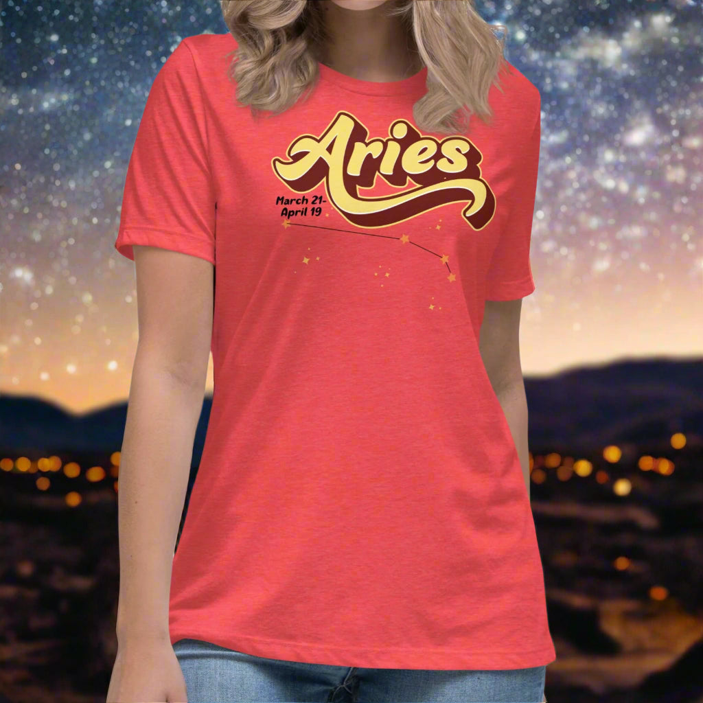 Woman wearing a heather red t-shirt facing forward. On the top is the word Aries in light yellow lined with maroon. Under the A are the dates March 21-April 19. Below his is the constellation Aries in bright yellow orange stars connected with a black line. Aries constellation zodiac astrology sign.