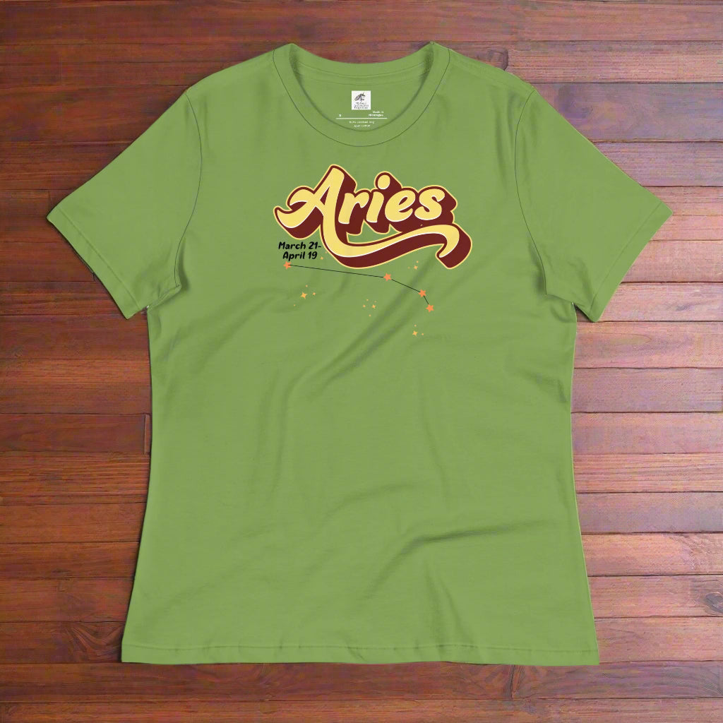 Aries Tee laying flat on a wooden counter, leaf green women's astrology t-shirt. On the top is the word Aries in light yellow lined with maroon. Under the A are the dates March 21-April 19. Below his is the constellation Aries in bright yellow orange stars connected with a black line. Aries constellation zodiac astrology sign.