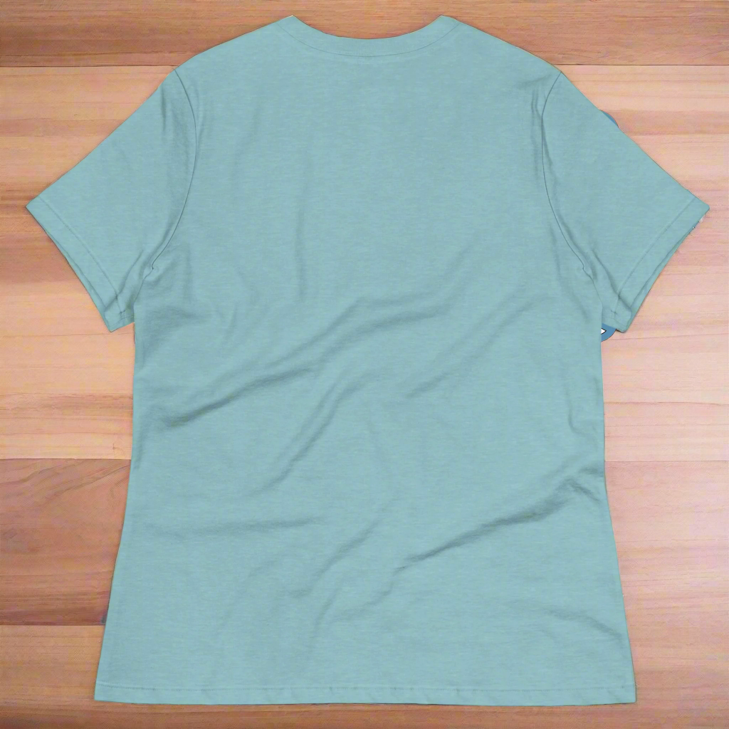 70s Vintage Peace Sign Women's heather blue lagoon T-Shirt back View on wooden counter. Purple Peace sign filled in with dragons, mermaids, fairies, unicorns, pegasi, witches, flowers, and butterflies.
