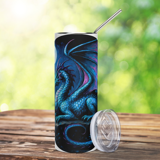 Insulated stainless steel fantasy dragon tumbler. This is a front view of a blue dragon with purple highlights on the wings, horns, and tail. The dragon is resting on an outcrop of rocks at night. There is a dark cloudy sky with a full moon. Graphic is in blues and purple. You can see the stainless steel straw sticking up from the tumbler. The clear plastic lid is leaning against the side of the tumbler. The graphic is on a white tumbler. 