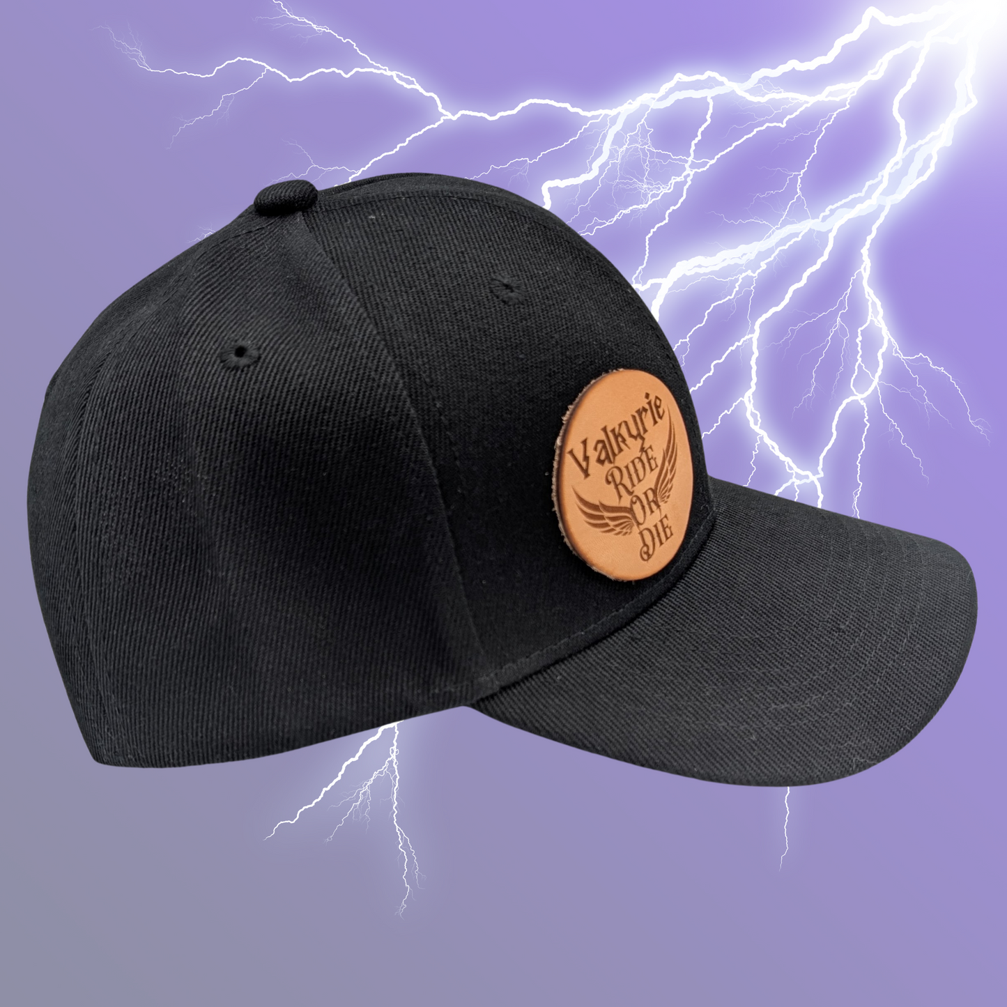 Right side view of black cotton snapback hat. On the front right side of the hat is a round leather patch. The leather patch is laser engraved with Valkyrie Ride Or Die. From the word Or wings spread out to both sides. Valkyrie Warrior Viking Hat