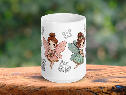White Ceramic Fairy Mug handle to the back. On the left you can see a Fairy with outspread pink butterfly wings, a pink dress, pointed ears, and brunette hair in a bun. To the right is the flying fairy with blue butterfly wings, blue dress, pointed ears, brunette hair in a bun with flowers. Between the fairies is the outline of a butterfly and a strawberry plant. To the left you glimpse the outline of flowers and a butterfly. FairyCore Coffee Mug