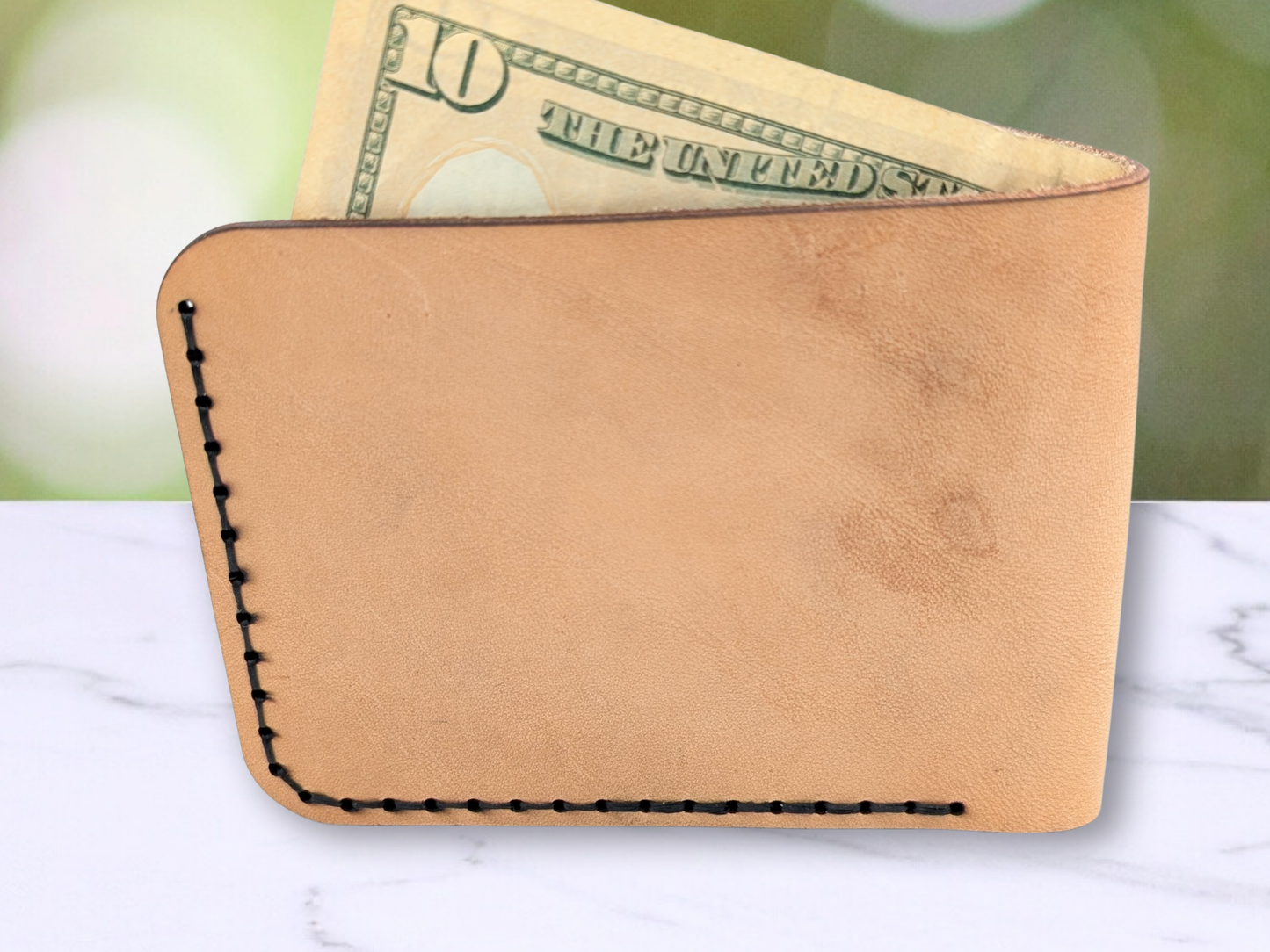 Veg Tan Leather handmade wallet back view showing black stitching with a $10 bill sticking up out of the cash compartment. 