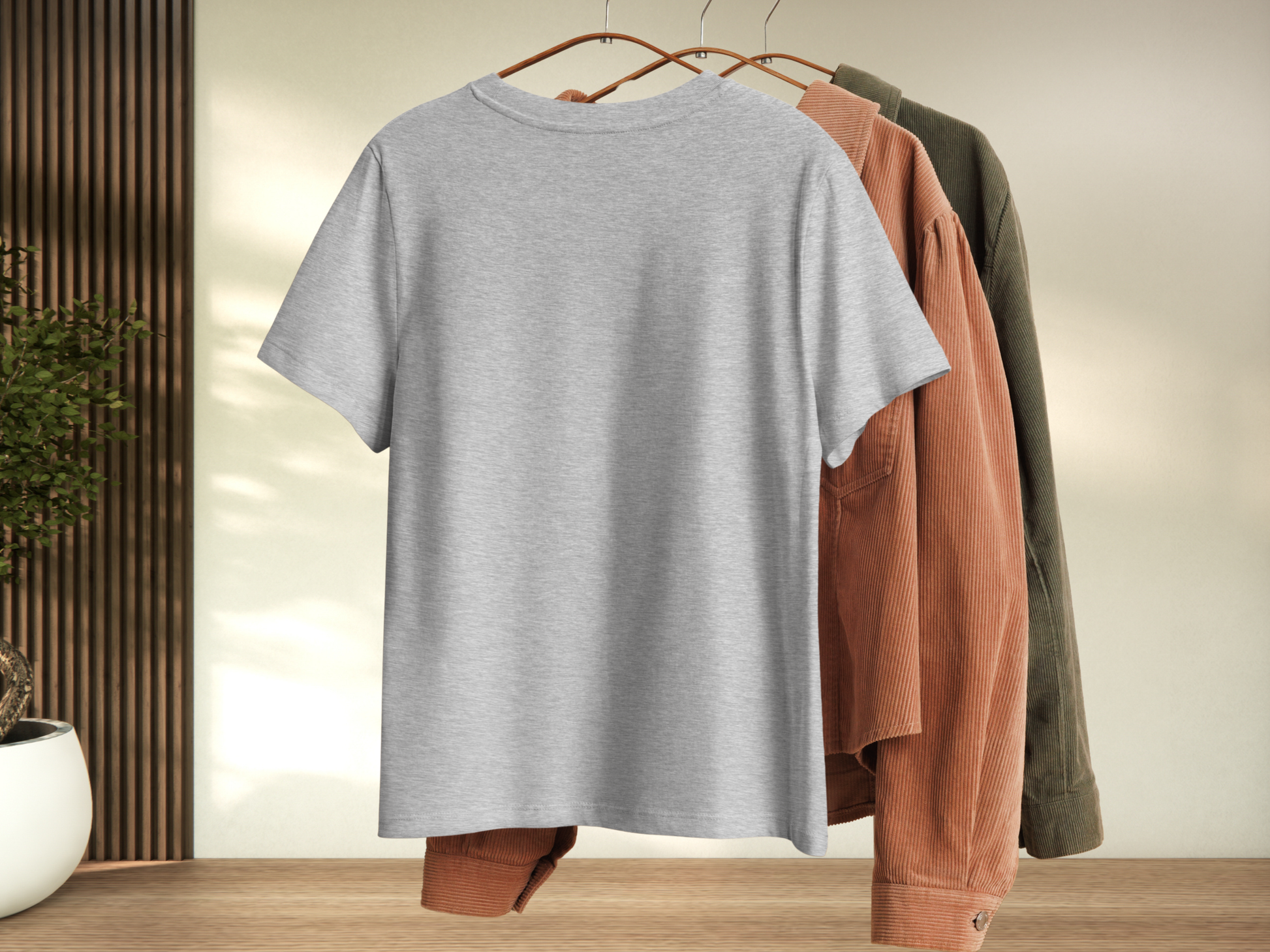 Athletic Gray t-shirt on a hanger with other clothing items in the background. Back View of Shirt