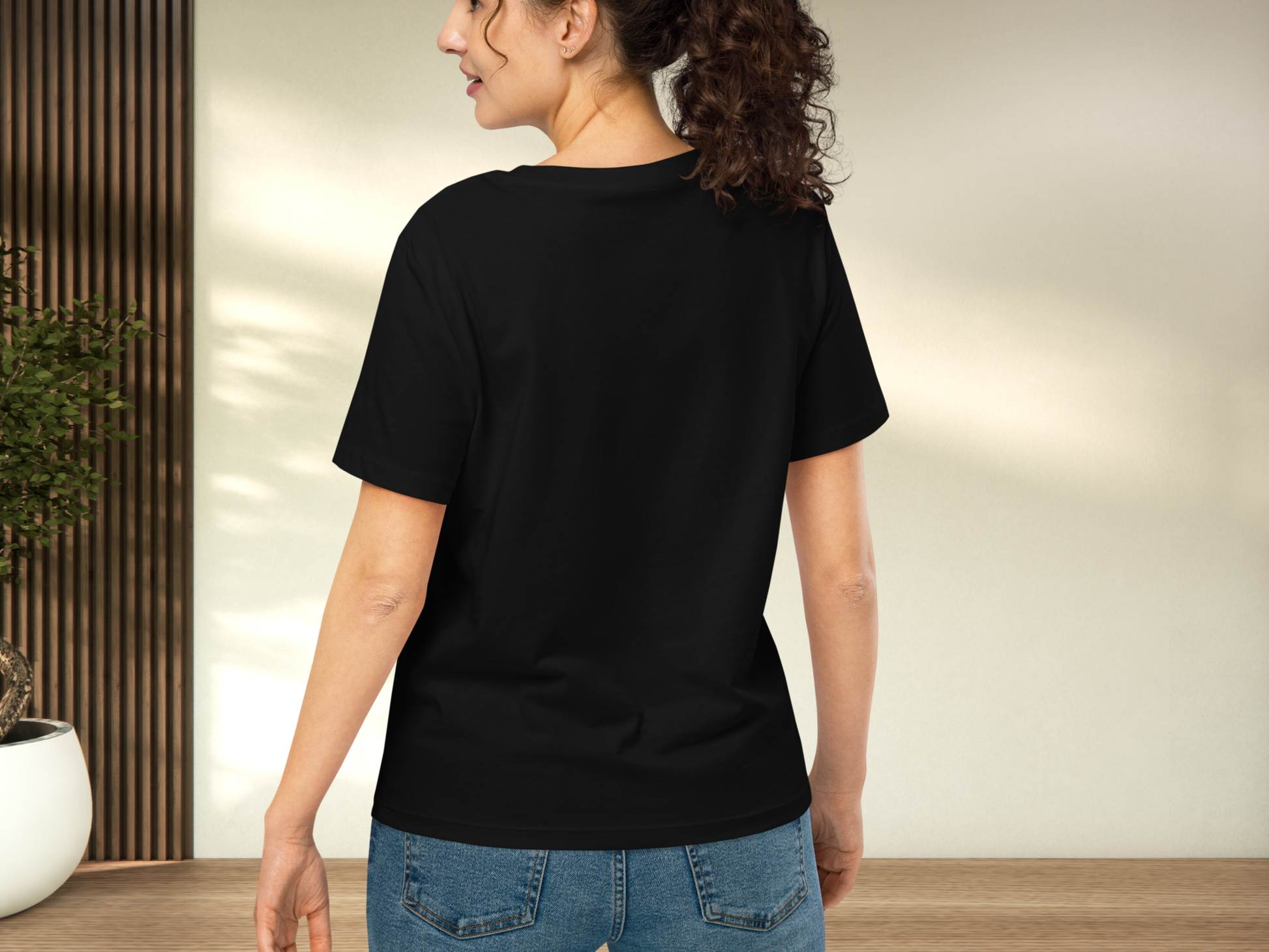 Model wearing a black t-shirt back view to show top of crewneck collar, sleeve length, hip fit, and hem length at mid hip.