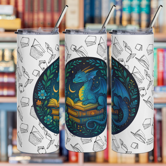 Book Dragon Graphic on White stainless steel 20 oz tumbler. Blue book dragon with horns perched on top of a stack of books. The top book is open for reading. Behind the dragon is the night sky with a crescent moon. Bordering the dragon are vines and flowers. Behind the circle graphic are black outlines of books surrounding the entire tumbler. In this photo you see the left side, front, and right side of the tumbler for a complete graphic. You see the metal straw sticking out of the top. Bookish Gift