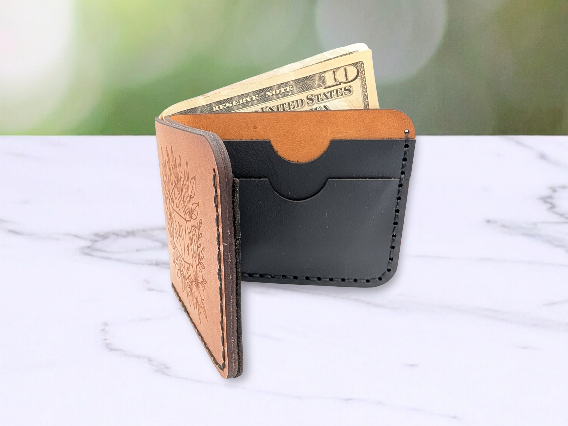 Veg tan leather wallet with D20 engraving. The wallet is standing on it's side and opened to see the dark edges of the leather, to see cash peeking out of the cash compartment, and the two black leather card pockets on the back side of the interior of the dad style wallet.