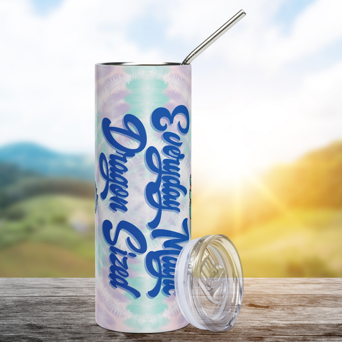 Everyday Magic Dragon Stainless Steel 20 oz Tumbler front view. BPA free plastic lid is leaning against the right side of the tumbler.  Against the tie dye background is text in a deep purple blue in a cursive script, Everyday Magic Dragon Sized. Fantasy Bookish Merch