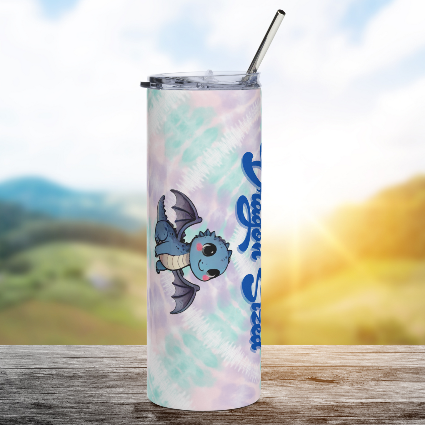 Everyday Magic Dragon Stainless Steel Tumbler left side view. You can see the bottom of the words Dragon Sized and below this you see a blue kawaii dragon with purple wings spread out.  The background is tie dye in greens, purple, and pinks. Book Lovers Gift