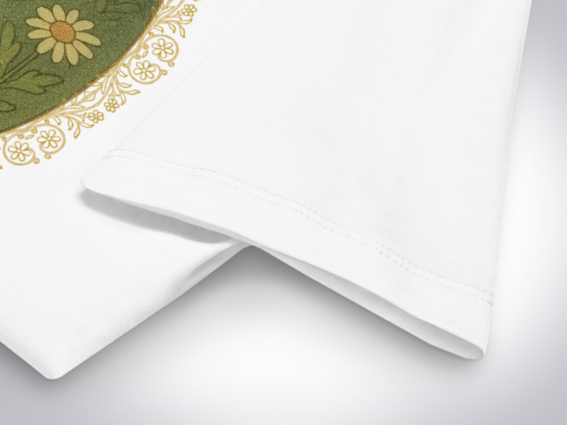 Close-up of a white tee to show the double needle stitching of the hem of the sleeve. You get a close up of the gold floral border that goes around the graphic.