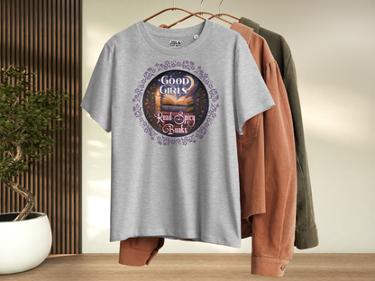 Athletic Grey Women's romantasy graphic tee on hanger, front view. Graphic has a purple floral frame around the circle graphic. The graphic has a botanical feel surrounding a stack of magic books with the top book open with light emanating from the book. A candle is lit nearby and a starry sky with a crescent moon is above the books. Above the books it states "Good Girls". Below the books it states "Read Spicy Books".