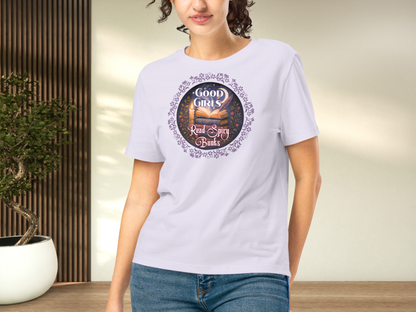 Model wearing a women's Romantasy Graphic Tee in lavender, front view. Graphic has a purple floral frame around the circle graphic. The graphic has a botanical feel surrounding a stack of magic books with the top book open with light emanating from the book. A candle is lit nearby and a starry sky with a crescent moon is above the books. Above the books it states "Good Girls". Below the books it states "Read Spicy Books".