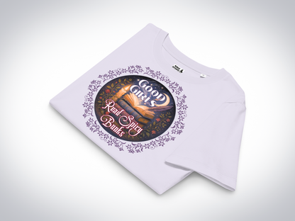 Romantasy Graphic Tee in Lavender folded, front view. Graphic has a purple floral frame around the circle graphic. The graphic has a botanical feel surrounding a stack of magic books with the top book open with light emanating from the book. A candle is lit nearby and a starry sky with a crescent moon is above the books. Above the books it states "Good Girls". Below the books it states "Read Spicy Books".